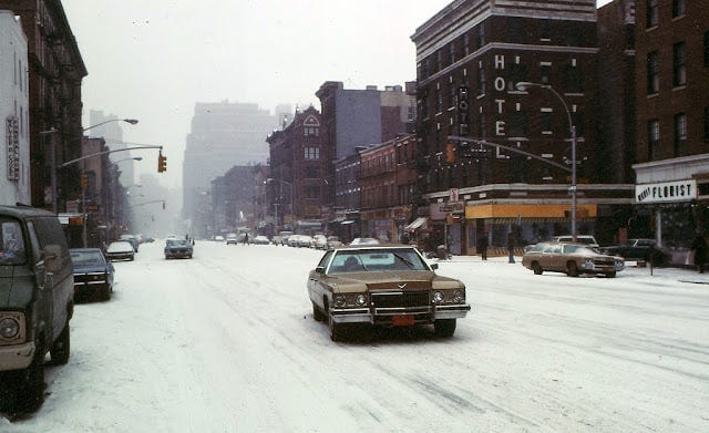Photo of a snow-covered street with cars on it in 1970s New York